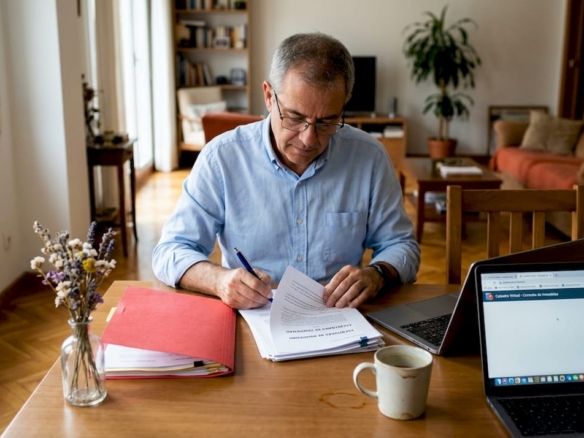 Un hombre revisa los papeles de su vivienda en la comodidad de su hogar.